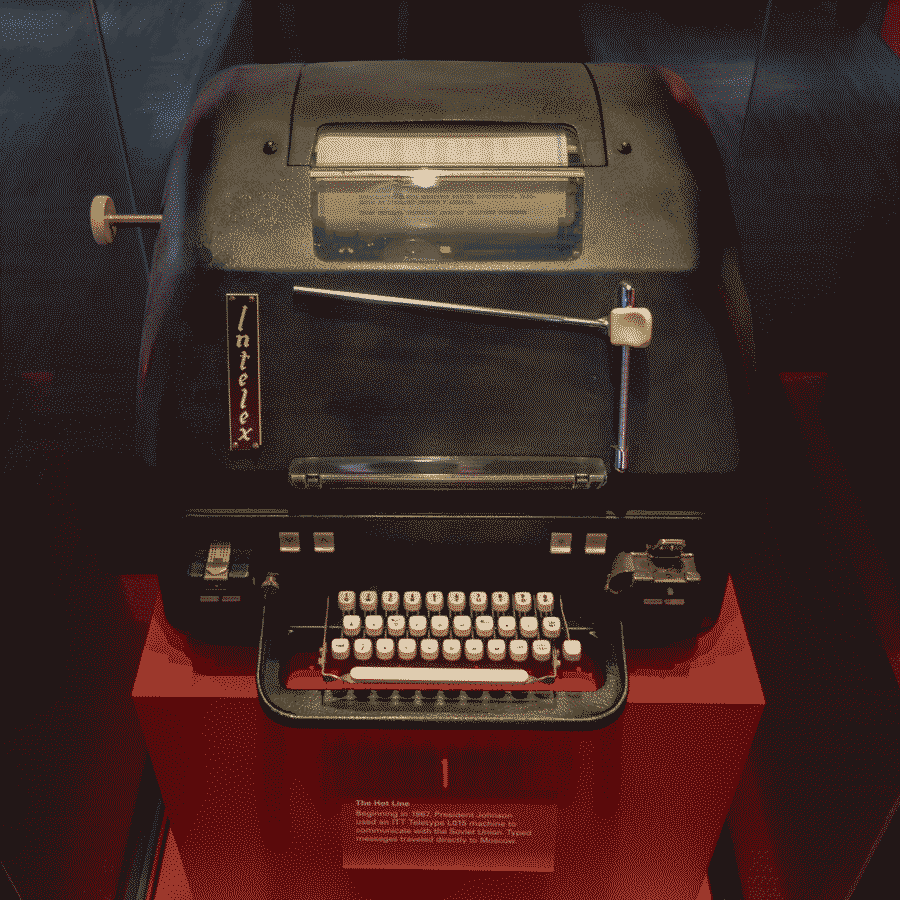A bulky teleprinter in a museum. The keyboard seems wery small compared to the massive size of the whole rounded, wide, and tall assembly.