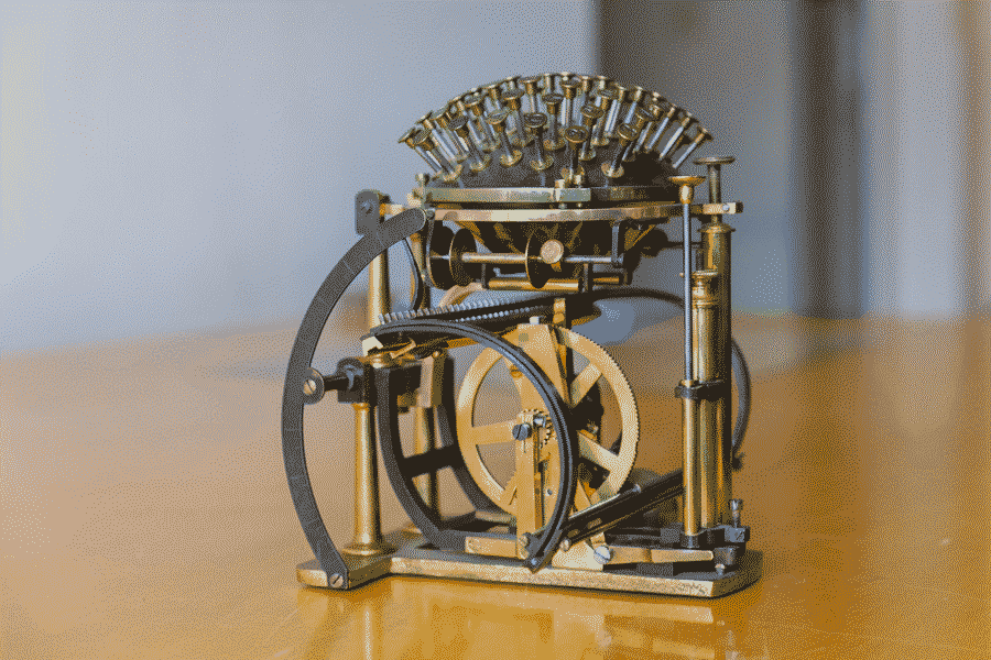 a museum photo of the Hansen Writing Ball typewriter. It is made mainly out of brass, with the keys sticking out of a half-sphere at the top like needles from the pincushion.